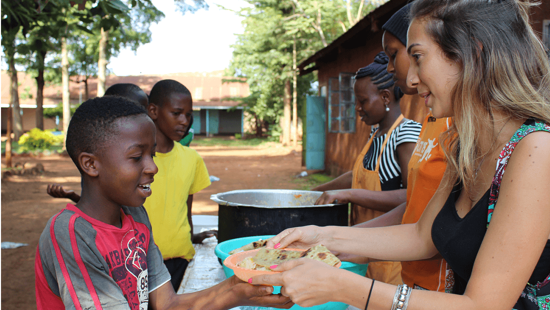 Volunteer serving food to a kid